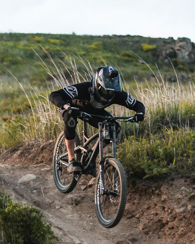 A mountain biker carving a berm on a forest trail